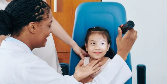 Doctor checking a small girl's eye.