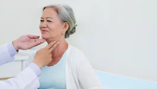 Doctor checking a old woman's eye for thyroid.