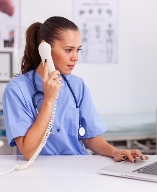 Medical practitioner answering phone calls and scheduling appointments in hospital office.